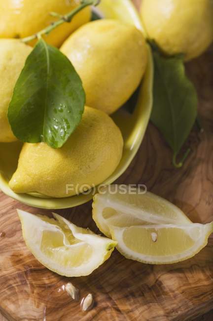 Limones maduros con cuñas y hojas - foto de stock