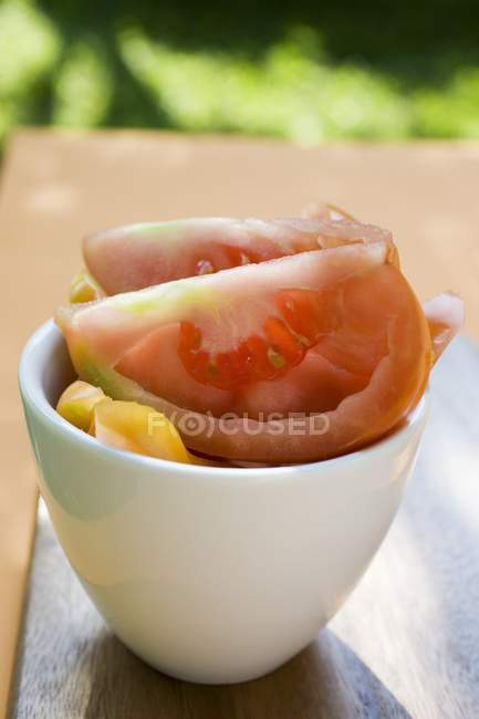 Cunhas de tomate em tigela branca sobre mesa — Fotografia de Stock