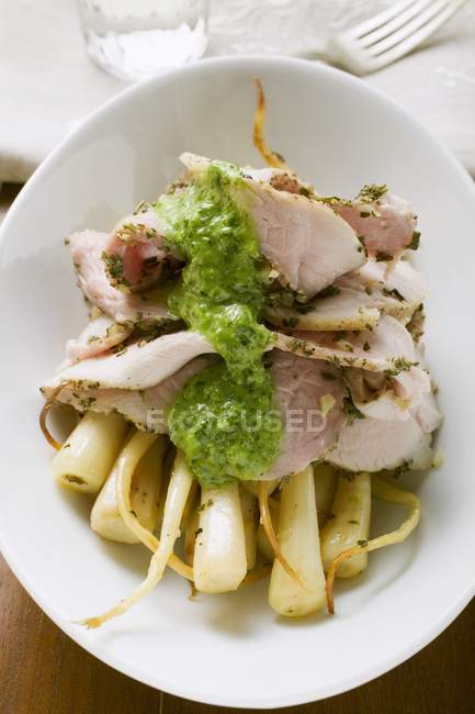 Turkey with herb sauce on root vegetables on white plate — Stock Photo