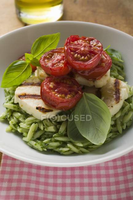 Green risoni pasta with pesto and tomatoes — Stock Photo