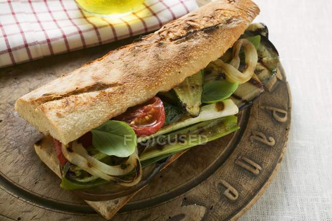 Baguette with grilled vegetables on wooden plate — Stock Photo