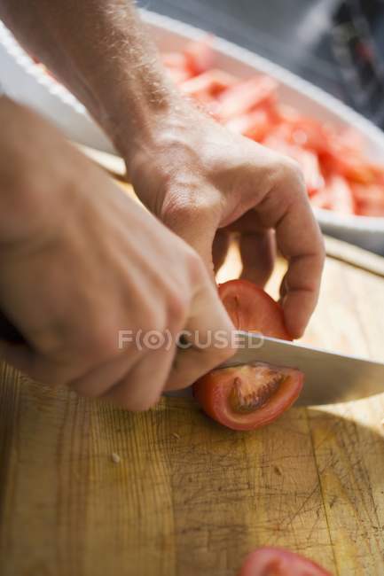 Manos masculinas rebanando tomates - foto de stock