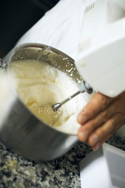 Vue rapprochée de la personne fouettant la crème avec un mélangeur — Photo de stock