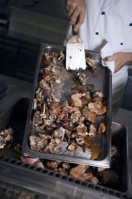Erhabener Blick auf Koch, der gebratene Hühnerstücke in Bratenform dreht — Stockfoto