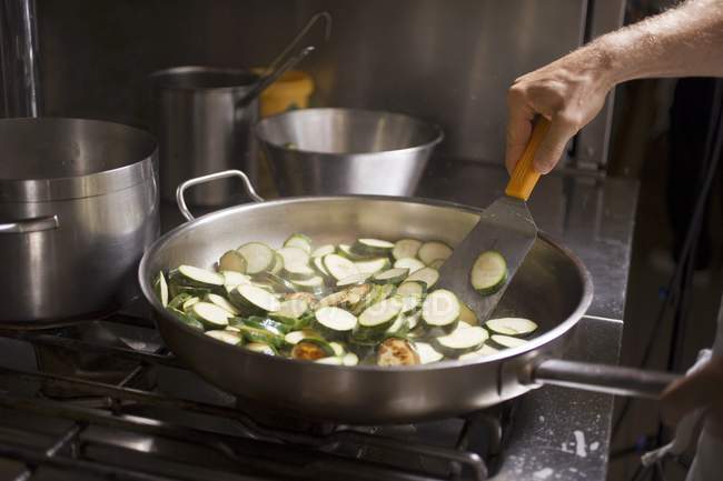 Turning courgette slices in frying pan — Stock Photo