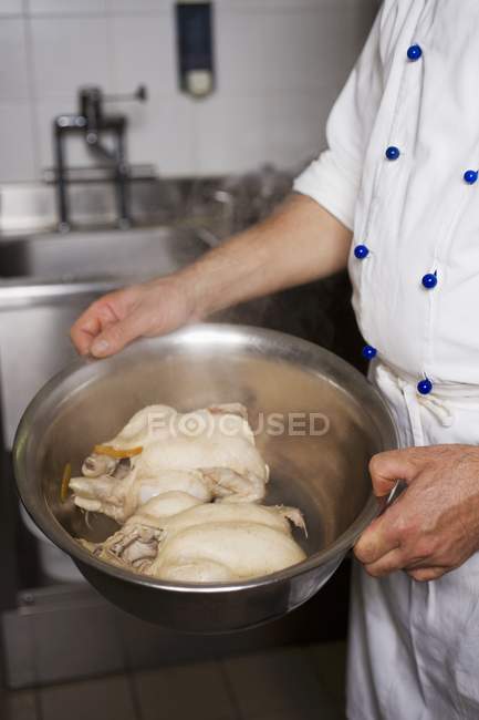 Cropped view of chef carrying bowl with two raw chickens — Stock Photo