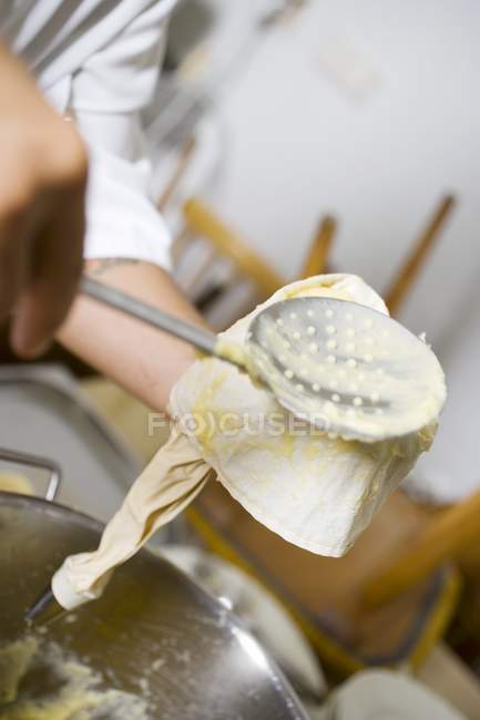 Cropped view of cook pressing cream into piping bag — Stock Photo
