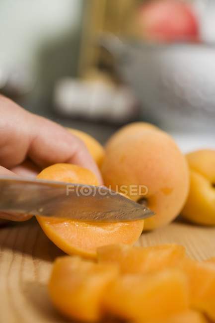 Человеческая рука режет абрикосы — стоковое фото