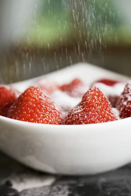 Polvilhar açúcar sobre morangos — Fotografia de Stock