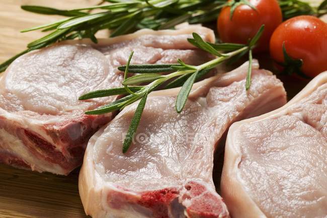Rohe Schweinekoteletts mit Rosmarin und Tomaten — Stockfoto