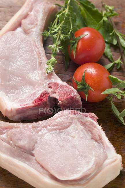 Raw pork chops with fresh herbs — Stock Photo