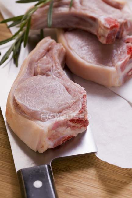 Raw pork chops with meat cleaver — Stock Photo