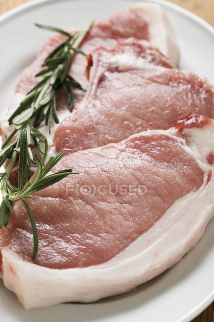 Raw pork chops with rosemary — Stock Photo