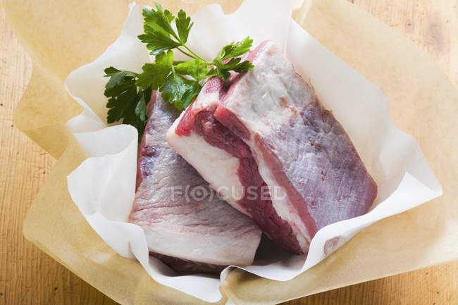 Frische Rindfleischstücke mit Petersilie auf Papier — Stockfoto