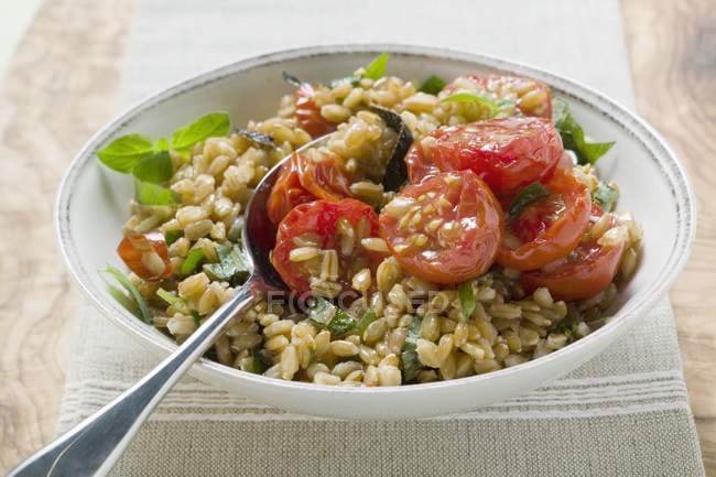 Emmer-Weizensalat mit Tomaten und Kräutern in weißem Teller mit Löffel — Stockfoto