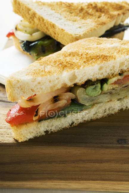 Sandwiches de verduras a la parrilla hechos con tostadas sobre superficie de madera - foto de stock