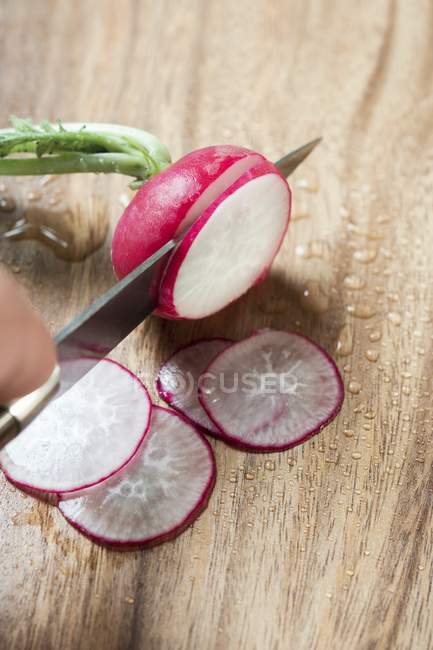 Human hand slicing radish — Stock Photo