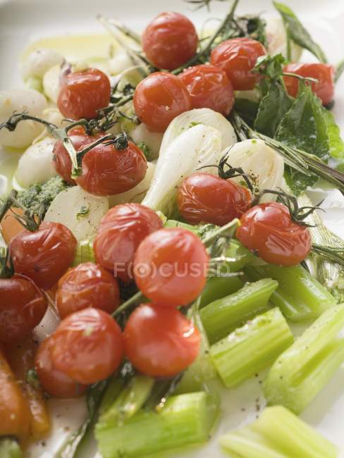 Pomodori ciliegia arrosto, sedano, cipollotti su piatto bianco — Foto stock