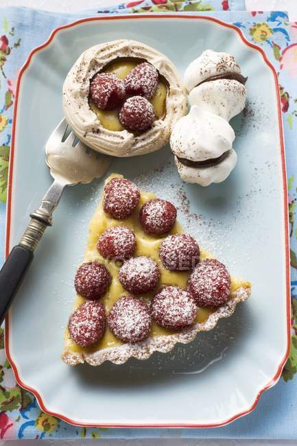 Piece of raspberry tart and filled meringues — Stock Photo