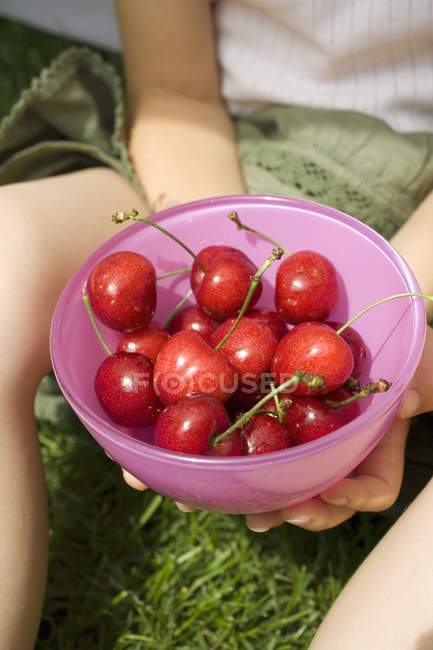 Mãos de criança segurando tigela de cerejas — Fotografia de Stock