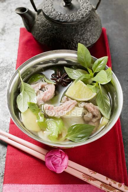 Hühner- und Zitronengrassuppe mit Limette, Thai-Basilikum in Schüssel über Handtuch mit Essstäbchen — Stockfoto