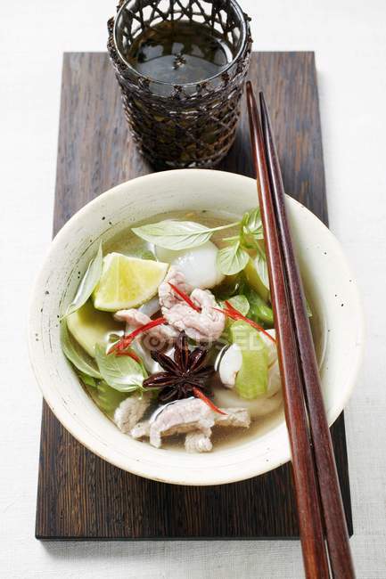 Closeup view of chicken and lemon grass soup with lime and basil — Stock Photo