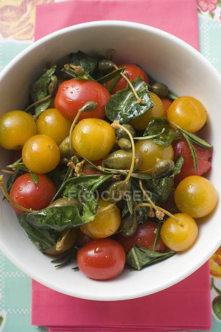 Ensalada de tomate con alcaparras y hierbas en tazón blanco - foto de stock
