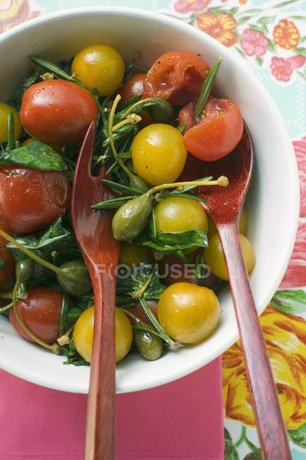 Tomatensalat mit Kapern und Kräutern in weißer Schüssel mit Gabel und Löffel — Stockfoto