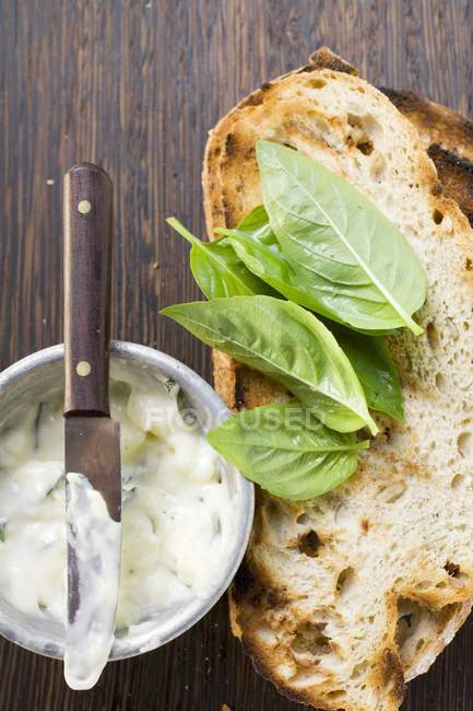 Basil mayonnaise and toasted bread on wooden surface with knife — Stock Photo