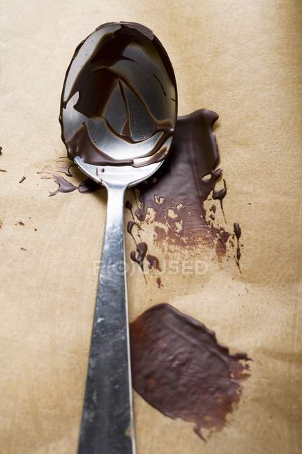 Closeup view of couverture remains on spoon and baking parchment — Stock Photo