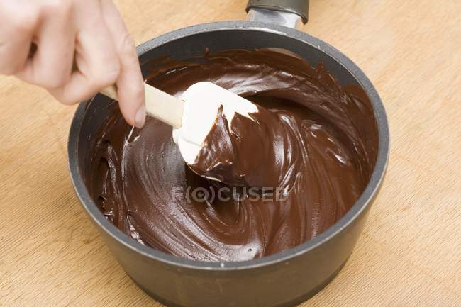 Menschliche Hand rührt geschmolzene Schokolade an — Stockfoto