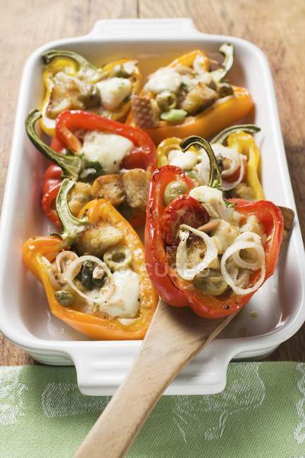 Peppers stuffed with white bread, olives, onions in white dish with wooden server — Stock Photo