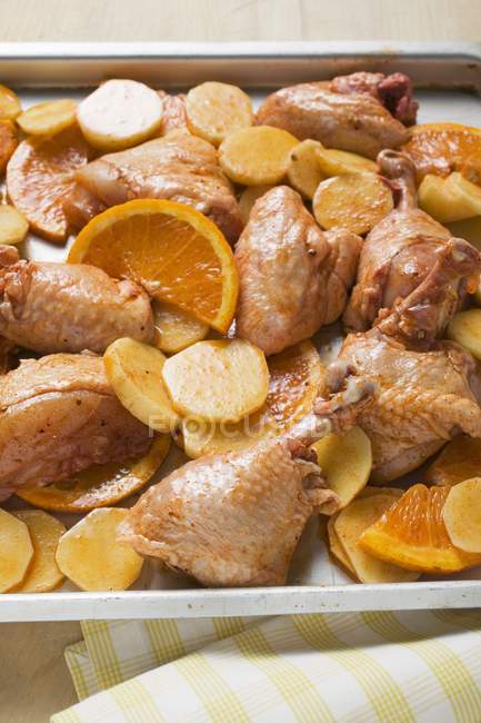 Trozos de pollo sin cocer con naranjas - foto de stock