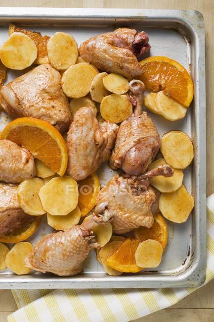 Uncooked chicken pieces with oranges — Stock Photo