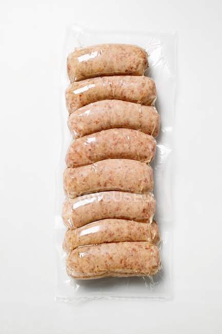 Вид сверху на колбасные ряды Сальсичче в упаковке на белой поверхности — стоковое фото
