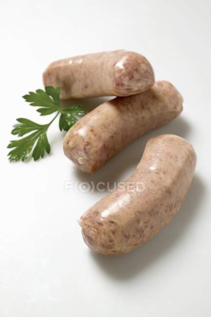Three Salsicce sausages with herb on white surface — Stock Photo