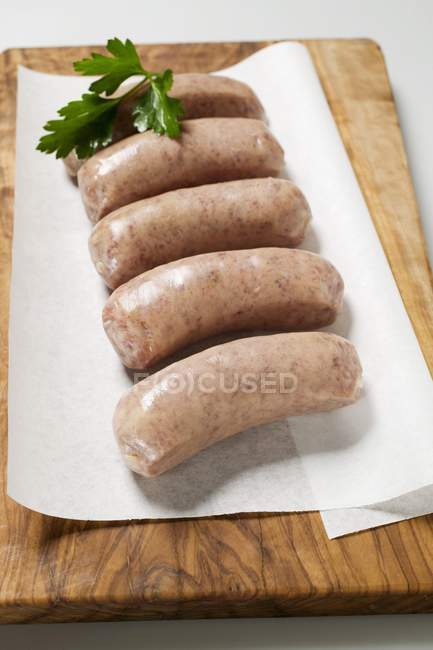 Closeup view of Salsicce sausages with herb on paper and chopping board — Stock Photo