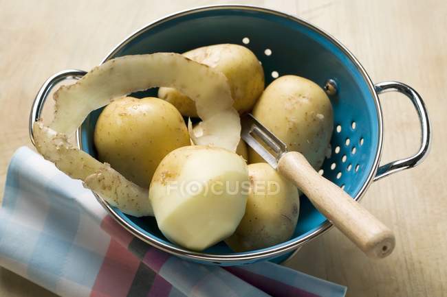 Batatas frescas e descascador — Fotografia de Stock