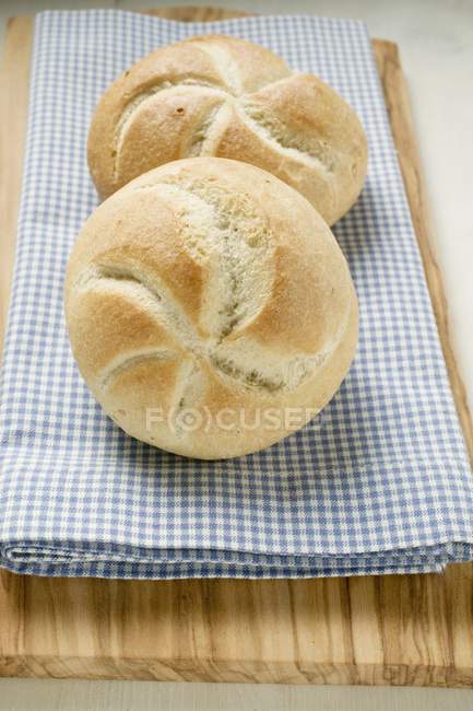 Rouleaux de pain sur tissu à carreaux bleu et blanc — Photo de stock