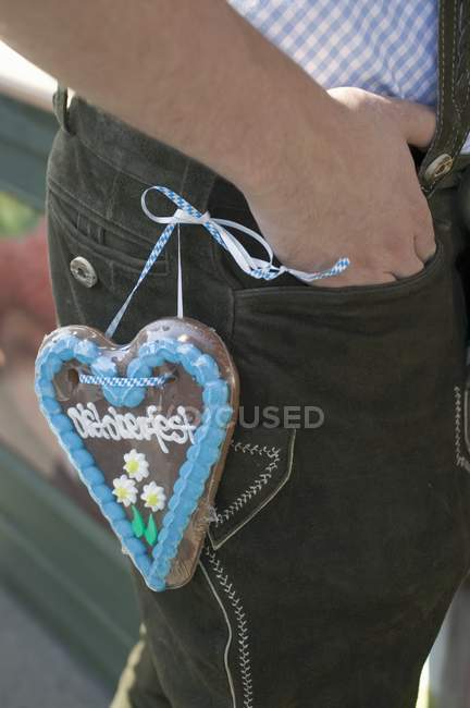 Cropped view of man with Lebkuchen heart on pants — Stock Photo