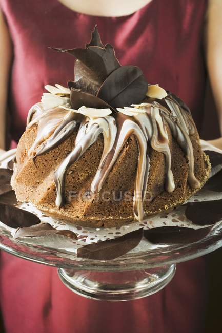 Closeup cropped view of woman serving Gugelhupf with chocolate and vanilla cream — Stock Photo