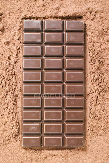 Barra de chocolate negro sobre cacao en polvo - foto de stock