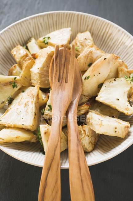 Roasted chunks of celeriac in dish with wooden spoon and fork — Stock Photo