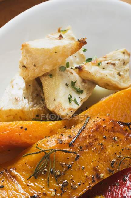 Roasted pumpkin slices and chunks of celeriac on white plate — Stock Photo