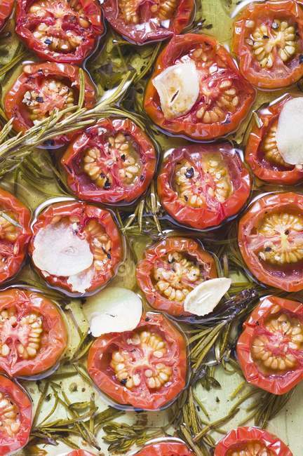 Close-up vista superior de tomates em óleo com alho e alecrim — Fotografia de Stock