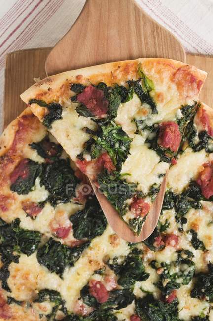 Pizza with slice on server — Stock Photo