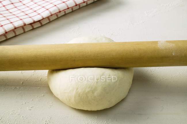 Pizza dough with rolling pin — Stock Photo