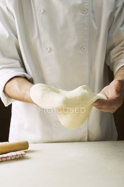 Шеф-кухар розтягує тісто для піци — стокове фото