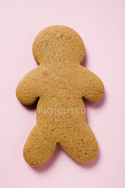 Closeup view of one gingerbread man-shape cookie on pink surface — Stock Photo