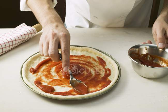 Шеф-повар раздает пиццу с соусом — стоковое фото